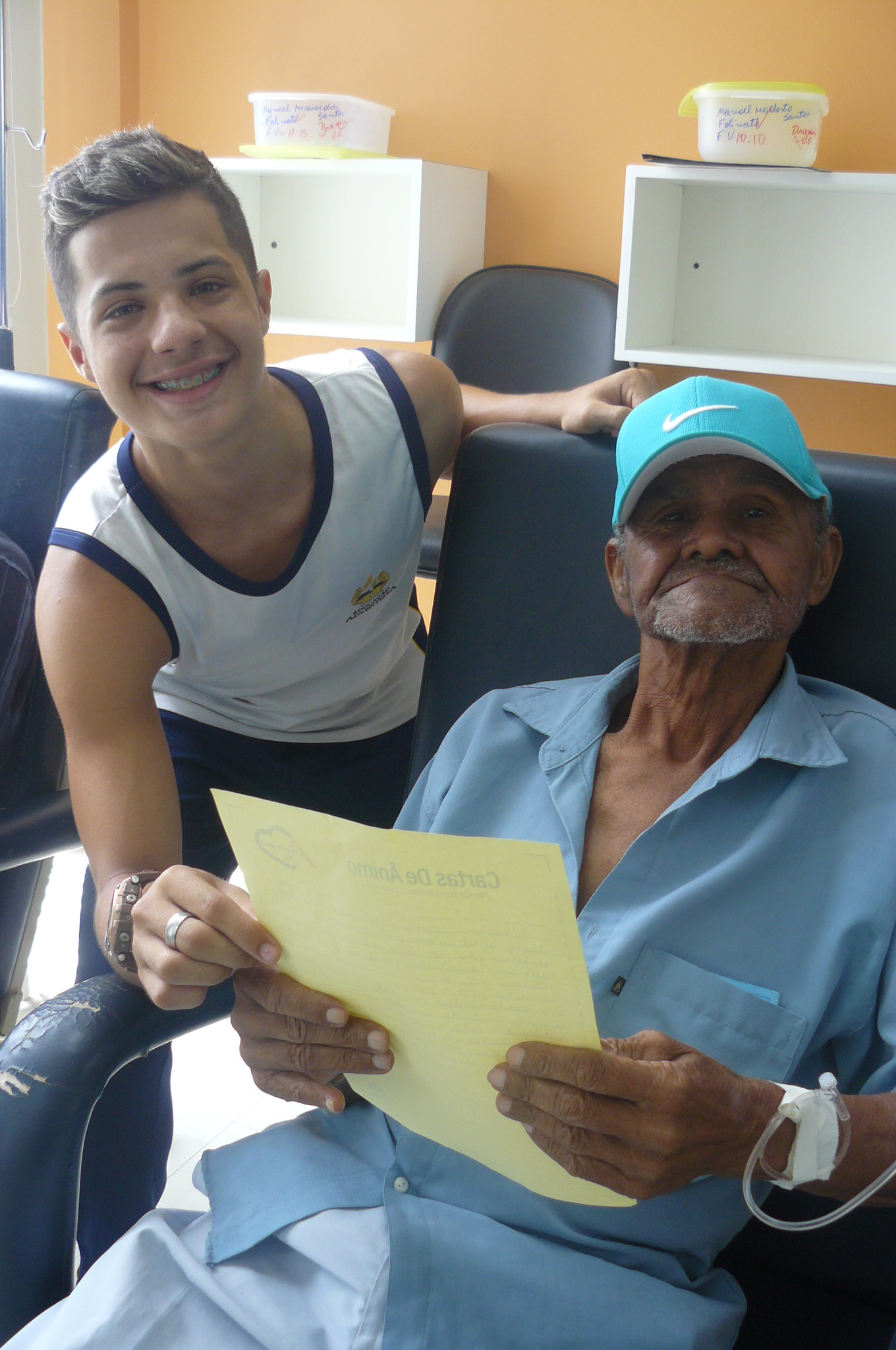O estudante, Volnei Júnior entrega cartinha de ânimo ao paciente Manuel.